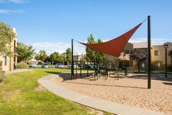 a park with a hammock and picnic table in front of a building